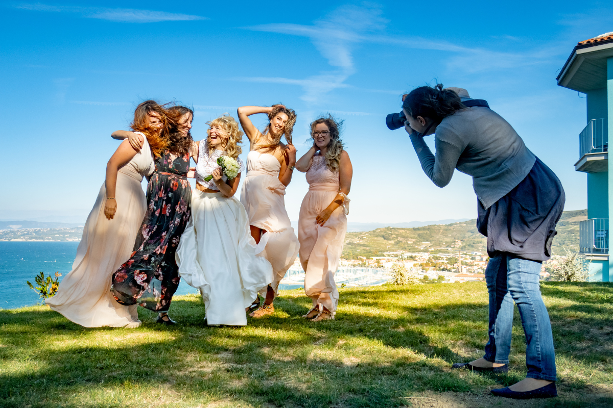 A talented female wedding photographer capturing joyful moments against a stunning ocean backdrop.