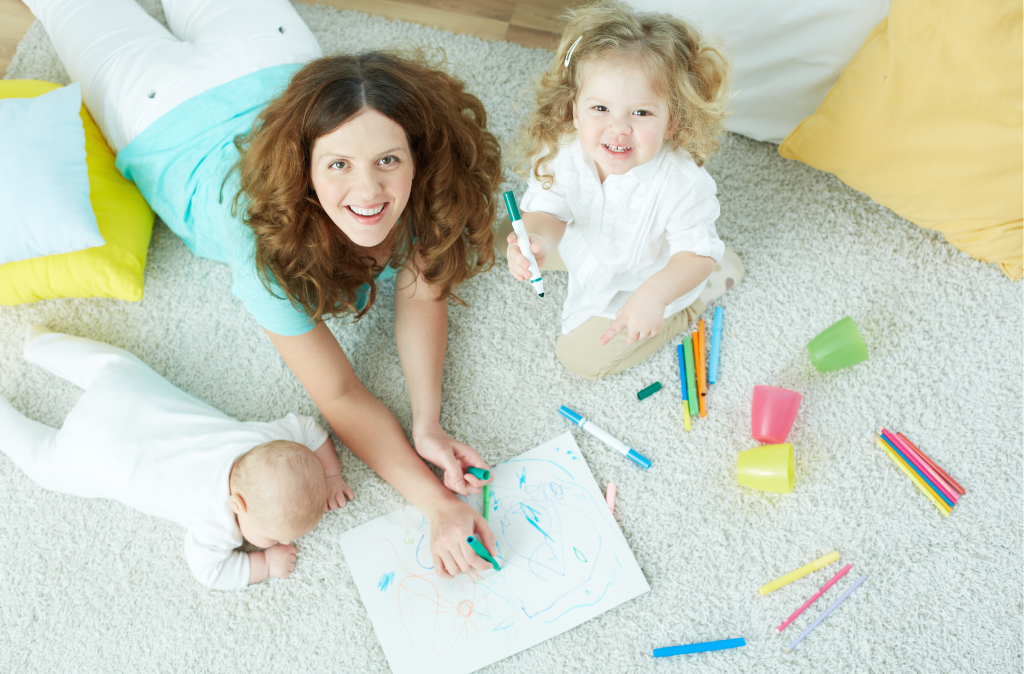 Babysitter drawing with a toddler and another child