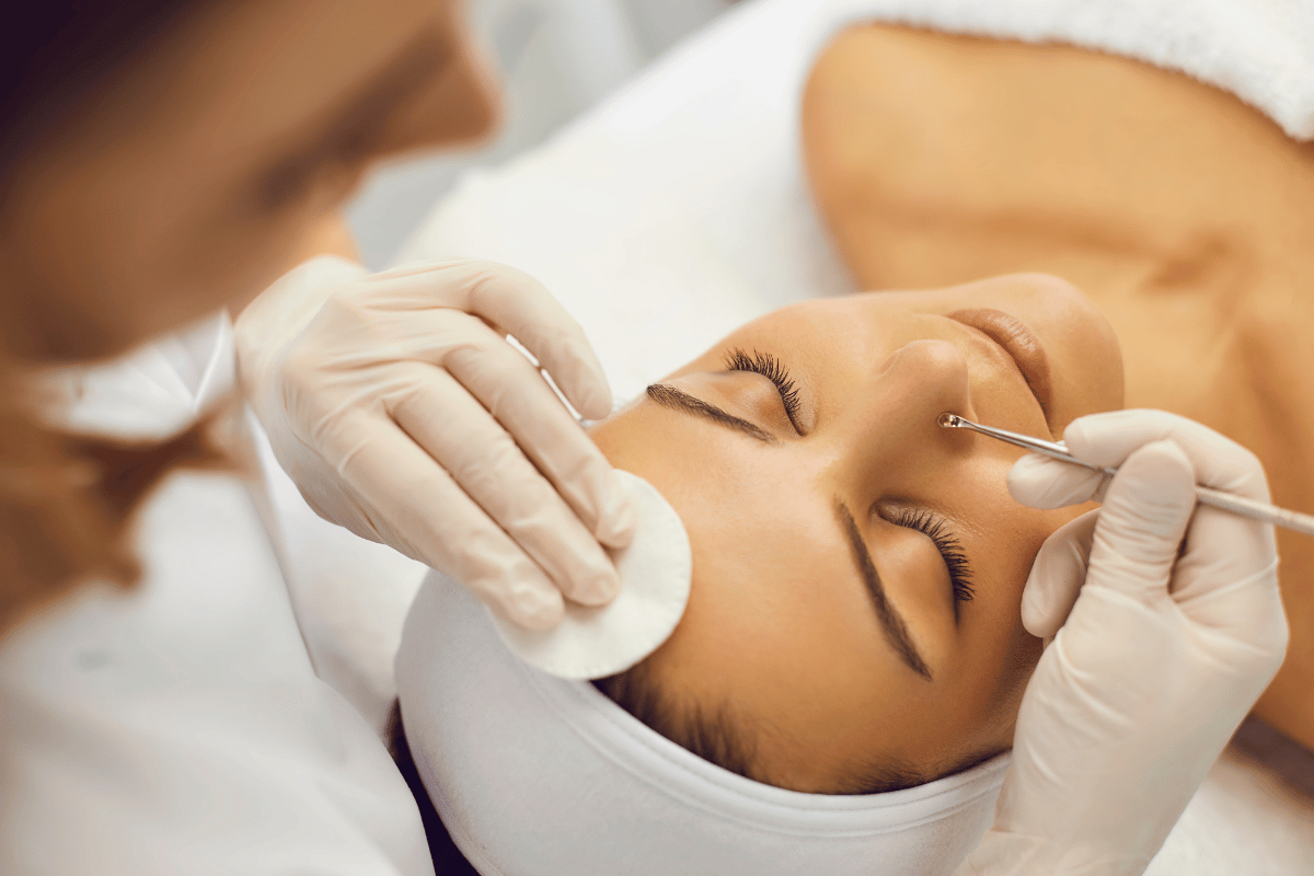 Professional esthetician performing an extraction facial on a woman, promoting clear and rejuvenated skin.