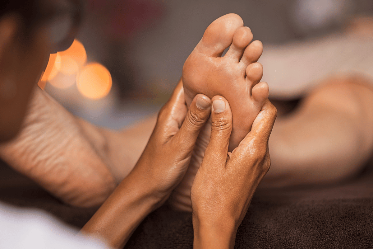 Closeup of masseuse doing foot reflexology to woman at spa. Therapist hands doing foot massage at wellness centre. Woman receiving a feet massage at health spa.