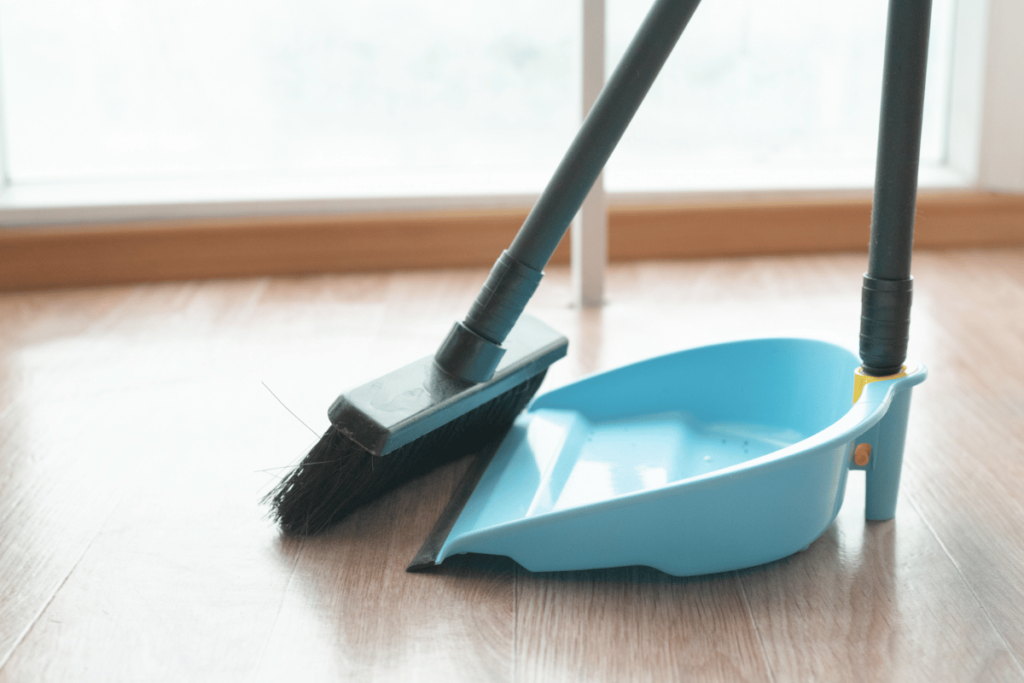A broom and dustpan on the floor close up.
