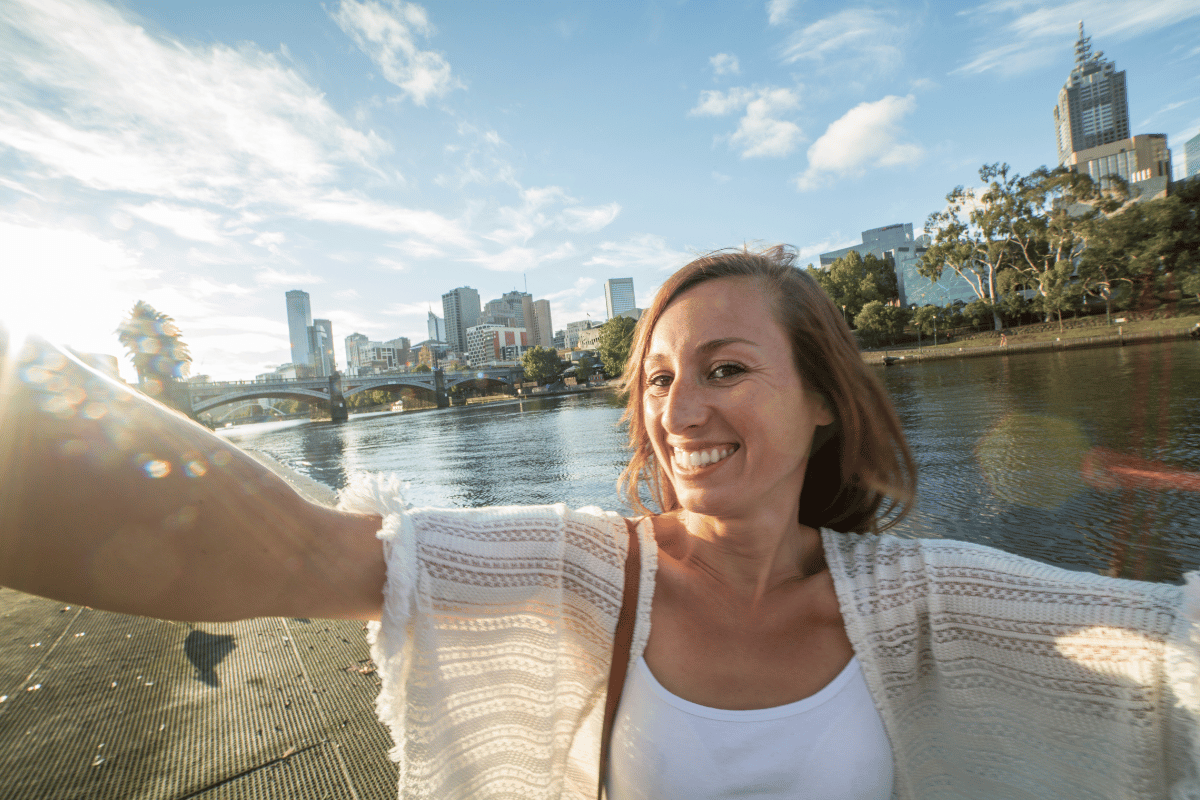 Cheerful young woman in Melbourne takes a selfie portrait along the Yarra River on a beautiful day.