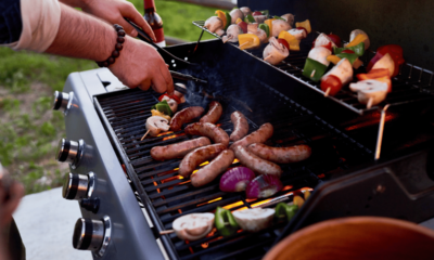 Chef cooking sausages and vegetables on BBQ skewers outdoors
