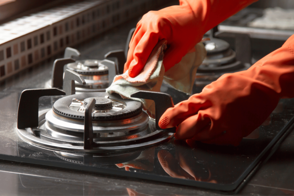 Hand in gloves Cleaning a gas stove at kitchen. house and kitchen cleaning service concept.