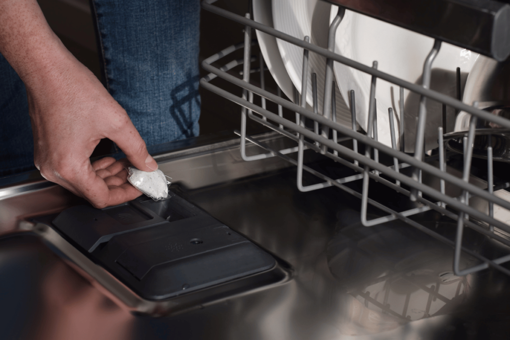 Woman placing detergent pod into dishwasher soap dispenser closeup