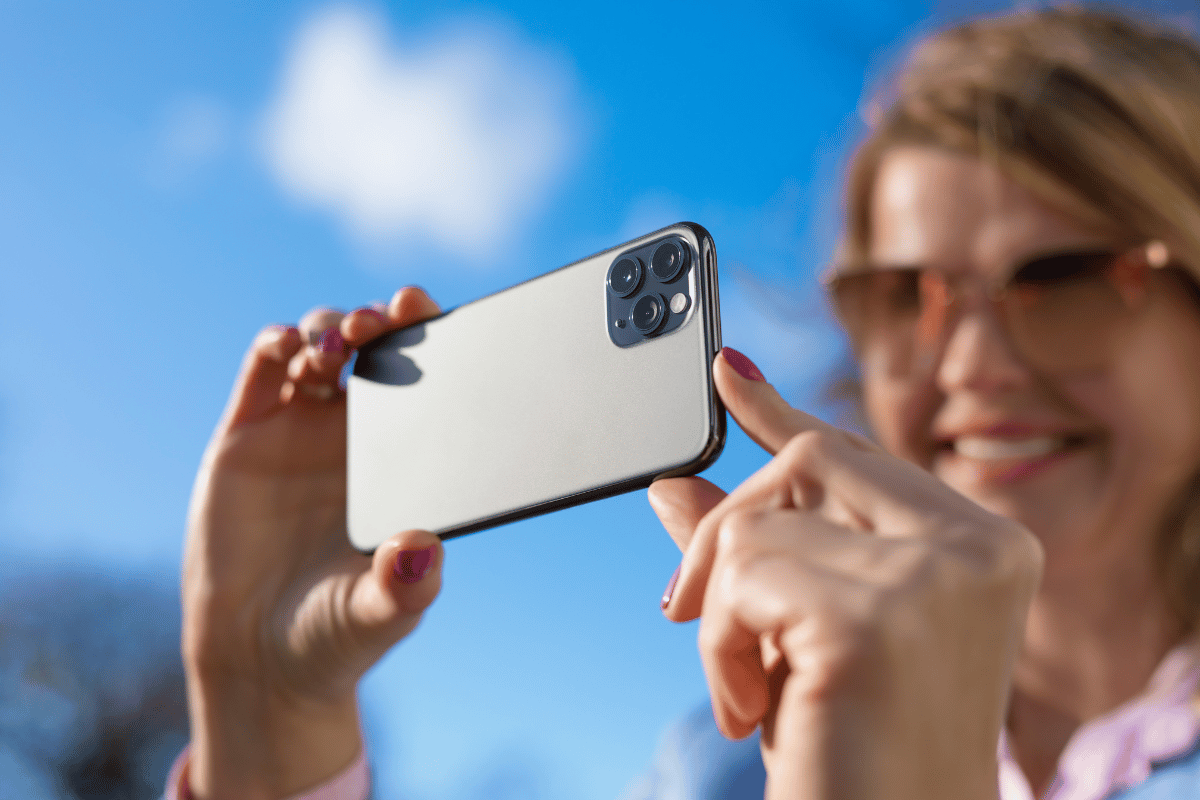 Woman taking photo with modern triple-lens camera phone