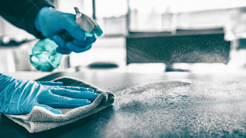 Cleaning home table sanitizing kitchen table surface with disinfectant spray bottle washing surfaces with towel and gloves.