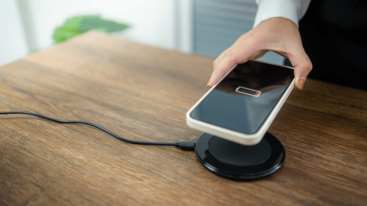 Charging iPhone battery with wireless charging device in the table.