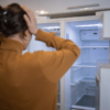Australian woman looking into an empty fridge amid rising food costs, Foodbank Hunger Report 2025.