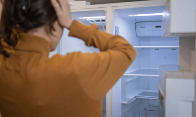 Australian woman looking into an empty fridge amid rising food costs, Foodbank Hunger Report 2025.