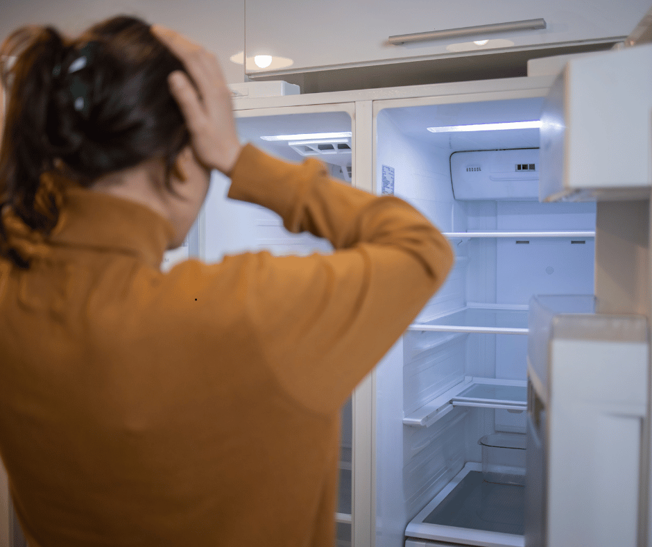 Australian woman looking into an empty fridge amid rising food costs, Foodbank Hunger Report 2025.