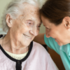 “Senior woman receiving support from a home caregiver, representing dementia care and daily living assistance.