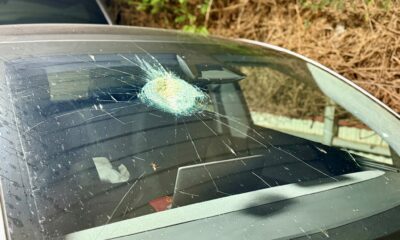 Close-up of a Tesla windshield showing a mysterious crater-like dent and melted glass, possibly caused by a meteorite impact.