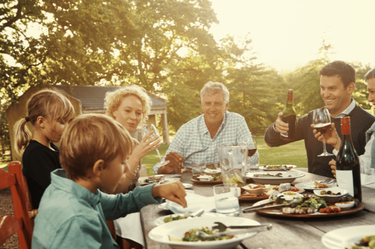 Family enjoying a relaxed outdoor meal together, representing sustainable abundance.