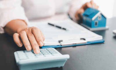 Person calculating borrowing capacity under APRA’s new DTI rules, with mortgage documents and a model house on the desk.”