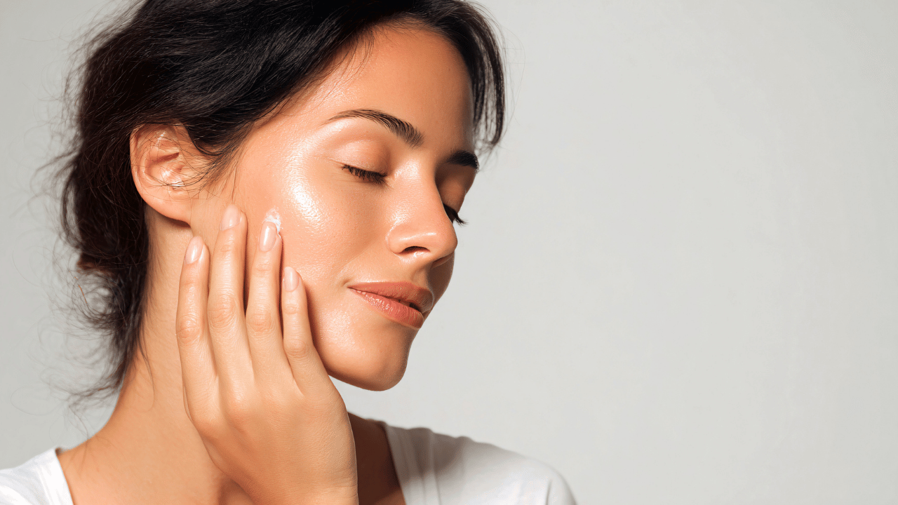 Woman applying facial moisturiser as part of a glowing skin routine