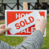 SOLD sticker being placed on a home for sale sign, reflecting rising Adelaide property prices.
