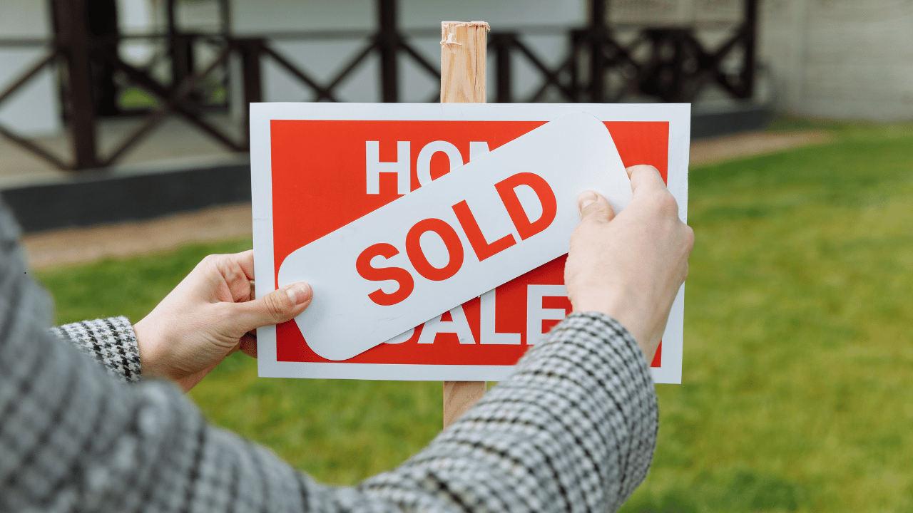 SOLD sticker being placed on a home for sale sign, reflecting rising Adelaide property prices.