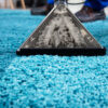 Professional steam carpet cleaning removing deep dirt from a blue carpet