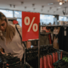 Shopper browsing discounted clothing racks, illustrating increased household spending activity.