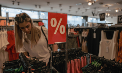 Shopper browsing discounted clothing racks, illustrating increased household spending activity.
