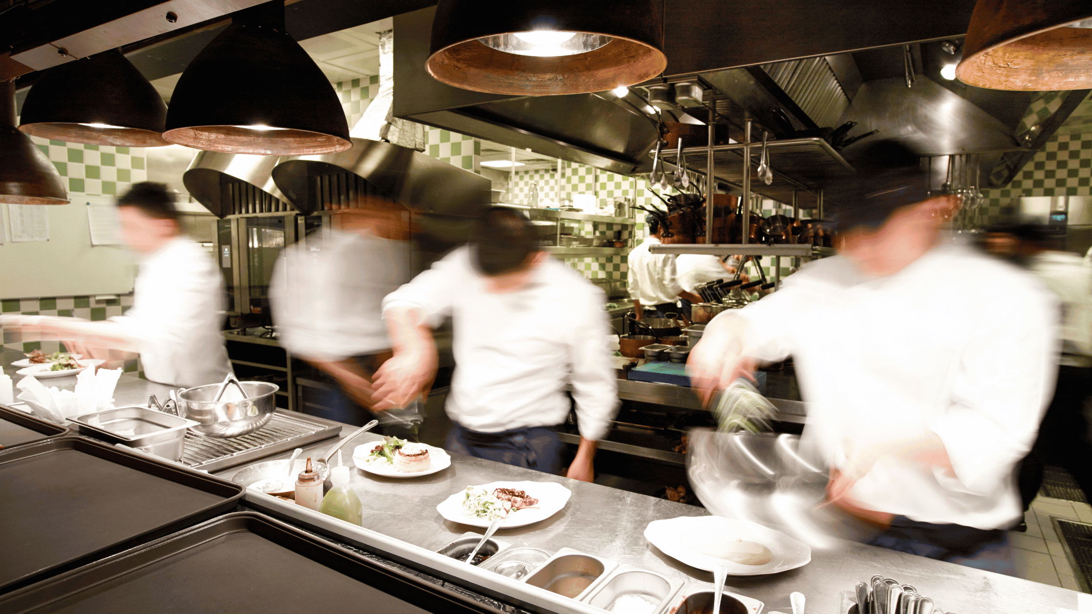 Busy restaurant kitchen during service showing labour intensity and operational pressure