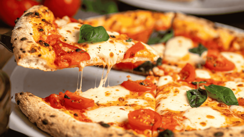 Slice of Margherita pizza with melted mozzarella, fresh basil, and cherry tomatoes