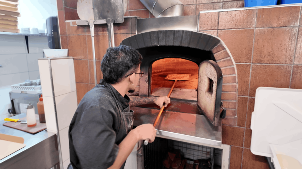 Chef placing a pizza into the wood-fired oven at Pizzeria Trieste in Port Lincoln.